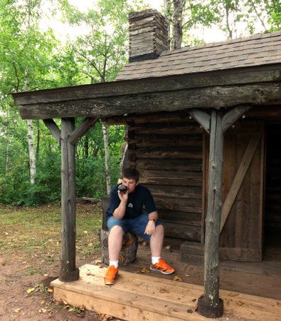Corbin sitting outside an old cabin