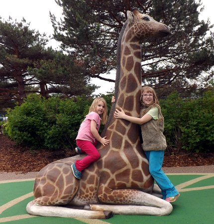 Anna and Ella climbing on a giraffe statue