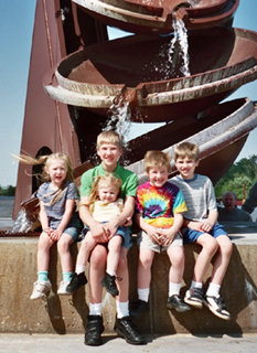 the kids posing in from of a statue and fountain